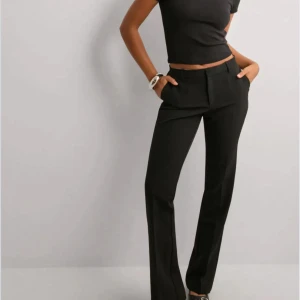 Lågmidjade kostymbyxor  - Snygga svarta kostymbyxor från Neo Noir med klassisk rak passform och låg midja. Byxorna är använda med ändå i väldigt bra skick inte noppriga osv, lite slitage vid knapparna fram men inget som påverkar! Jag är 170 cm o längden är perfekt för mig. Nypris är 699kr 