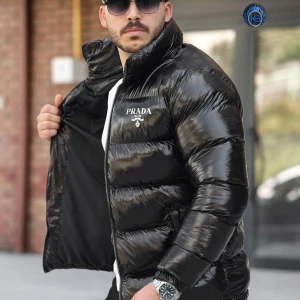 Svart pufferjacka från Prada - Säljer en svart, glansig pufferjacka från Prada med hög krage och tydlig logga på bröstet. Jackan har dragkedja framtill och är riktigt fet för kalla dagar. Perfekt för dig som vill ha en stilren och lyxig look.Fråga gärna om storlek S/M/L/Xl/XXL