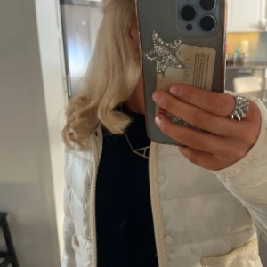 Vit quiltad pufferjacka Gina Tricot - Snygg vit pufferjacka från Gina Tricot med quiltad design och två stora fickor framtill. Jackan har rund halsringning, knäppning med tryckknappar och fina flätade detaljer längs kanterna. Perfekt för dig som vill ha en stilren och trendig look.