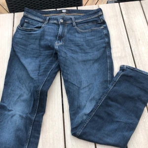 Blå tapered jeans Pearson 521 32/32 - Snygga blå jeans från Pearson, modell 521 med tapered fit. Klassisk femficksdesign, tydliga kontrastsömmar och läderpatch bak i midjan. Jeansen är i kraftig denim och har en rak men avsmalnande passform som ger en modern look. Skick 10/10 använda 1gång. Hör av er vid frågor 