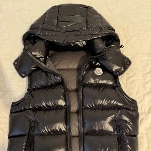 Svart dunväst från Moncler  - Hej! Säljer min väst eftersom jag har köpt en ny, den är i jättebra skick fast kvitto saknas, köptes från en vän, storleken är S men kan passa M också, vid intresse kan fler bilder skickas, åsikter kan diskuteras till en överenskommelse 😊.