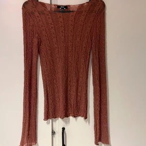 spetsblus från MNG - Säljer en tunn och transparent blus från MNG med lång ärm. Blusen har ett spetsmönster med vertikala ränder och lätt vågig kant nedtill. Materialet är mjukt. Har ett litet hål i ena ärmen 