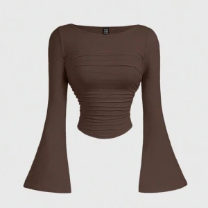 Brun croppad topp med utsvängda ärmar - Säljer en brun croppad topp med långa utsvängda ärmar och rynkade detaljer framtill. Toppen har en tight passform över kroppen och är perfekt för dig som gillar trendiga siluetter. Materialet är mjukt och stretchigt, vilket gör den superbekväm.