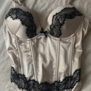 Champagnefärgad korsettopp H&M spets - Champagnefärgad korsettopp från H&M med svart spets jätte fin finns inte och få tag på nånstans, köpte för 500, jätte fin aldrig använd💞