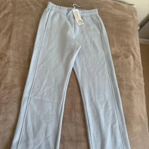 Ljusblå mjukisbyxor från Amisu - Snygga ljusblå mjukisbyxor från Amisu med elastisk midja och dragsko. Byxorna har raka ben och är tillverkade i mjuk bomullsmix som känns skön mot huden. Perfekta för chill dagar eller när du vill ha en avslappnad stil.