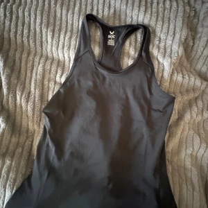 Svart träningslinne  SOC - Säljer en svart, ärmlös träningstopp från SOC med brottarrygg. Perfekt för gymmet eller löprundan, i ett stretchigt och bekvämt material som andas. Snygg och enkel design som passar till allt.