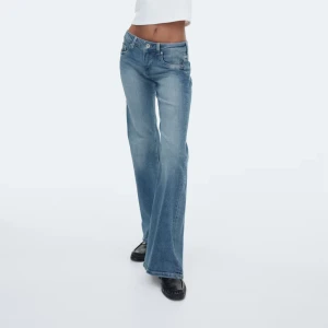 Blå bootcut jeans med låg midja - Snygga blå jeans med bootcut passform och låg midja. Jeansen har klassisk femficksdesign, lätt tvättad look och är tillverkade i mjukt denimtyg. Perfekta för dig som gillar en retro vibe och vill ha ett par jeans som sticker ut.