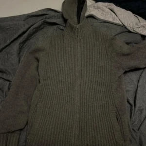 Grå ribbad hoodie från Massimo Dutti - Säljer en grå hoodie från Massimo Dutti med ribbad struktur och dragkedja framtill. Tröjan har huva, långa ärmar och är stickad i mjukt material. Den är i väldigt bra skick. 