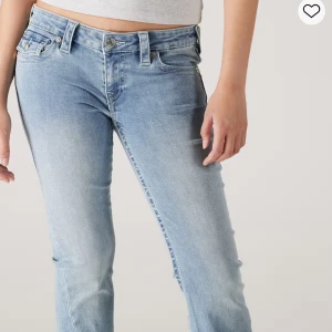 True Religion Joey ljusblå flare jeans - Säljer ett par True Religion Joey jeans i ljusblå tvätt med låg midja och utsvängda ben. Klassiska detaljer som stora bakfickor med lock och silverfärgade knappar. Säljer eftersom jag inte använder dem. Nypris: 1299kr