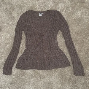 Brun stickad kofta från isolde - Mysig brun stickad kofta från Seld med lång ärm, v-ringning och knytband framtill. Koftan har ett snyggt virkat mönster nertill och ribbade partier upptill. Perfekt för lager-på-lager och chill höstkvällar. Passar även xs/s