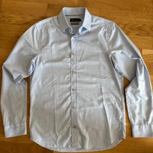 Ljusblå Riley skjorta  - Säljer min ljusblåa Riley skjorta för bra pris. Produkten har bara används ett fåtal gånger på evenemang som bröllop och småfester. Den har bara används i max 10 gånger och köptes originellt för 699kr