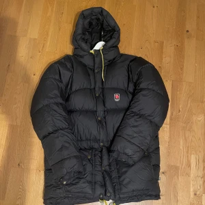 Svart expedition Fjällräven M - Säljer en svart, dunjacka från Fjällräven i storlek M. Sparsamt använt under 1 vinter från jag köpte den. Inga deflekter. Vill bli av med den därav priset, hör gärna av dig om du vill ha mer bilder!