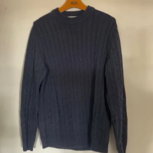 Mörkblå kabelstickad tröja S - Mysig mörkblå kabelstickad tröja med rund hals och långa ärmar. Tröjan är en lite mer ”lose fit” och hög hals.