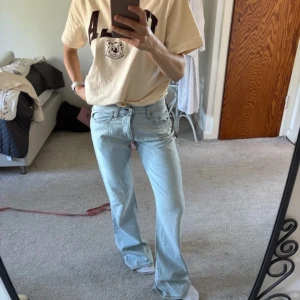 Ljusblå lågmidjade jeans  - Säljer ett par ljusblå jeans med bootcut passform och låg midja. Jeansen har klassisk femficksdesign, dragkedjegylf och är tillverkade i mjukt denim. Perfekta för dig som gillar en avslappnad och retro vibe.