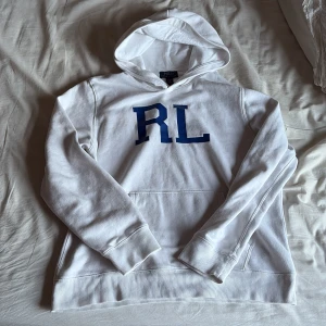 Vit hoodie från Polo Ralph Lauren - Säljer nu min vita hoodie från Polo Ralph Lauren i storlek barn XL. Tröjan har blå RL-tryck på bröstet, klassisk huva och magficka. Tröjan sitter som en S/M och vid bild me den på är de bara o skriva. Passar dig mellan 180-185 cm. Vid minsta lilla fråga är de bara o skriva!🙌