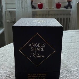Kilian Angels' Share Eau de Parfum 50ml - Exklusiv parfym från Kilian, Angels' Share, i en lyxig kristallin glasflaska med guldtonad vätska. Flaskan har ett elegant mönster och levereras i en svart, stilren ask med gulddetaljer. Volymen är 50 ml Eau de Parfum.