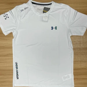 Vit Under Armour t-shirt i  - Fräsch vit t-shirt från Under Armour med tryckt logga på bröstet och textdetaljer på axel och sida. Skön passform och tillverkad i syntetmaterial som andas, perfekt för träning. Klassisk rund hals och korta ärmar.