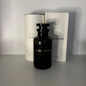 Louis Vuitton Ombre Nomade parfym sampel - Lyxig parfym från Louis Vuitton, Ombre Nomade, i en elegant mörk glasflaska med guldfärgad text. Flaskan har en rund form och svart lock. Kommer med originalförpackning i vitt och guld. Perfekt för dig som gillar exklusiva dofter.