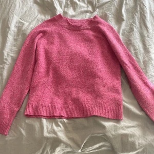 Rosa stickad tröja från Vero Moda - Mysig rosa stickad tröja från Vero Moda i storlek S. Tröjan har en klassisk rund halsringning, ribbade muddar och är långärmad. Perfekt för lager-på-lager och passar till både jeans och kjol. Som ni ser på bilden är den lite nopprig men annars super bra skick. 