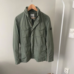 J. Lindeberg field jacka  - Säljer denna jättefina fieldjackan ifrån J. Lindeberg i storleken small. Jättefint skick, dock ett litet hål bredvid märket på ärmen men inget som syns vid användning. Nypris ligger runt 3500 till 4000! Mitt pris 1499 Mått Total längd: ca 80 cm Armlängd: 60 cm Bröstbredd 40 cm