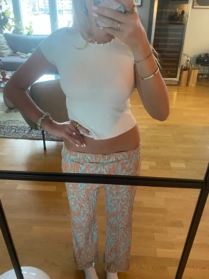 Mönstrade vida byxor i blått och orange - Säljer ett par riktigt snygga vida byxor med blått och orange mönster. Byxorna har låg midja och är gjorda i ett lätt, flowy material som känns perfekt för varmare dagar. De har ett unikt print och sitter löst hela vägen ner. Säljer dom eftersom dom tyvärr är för korta på mig 😢