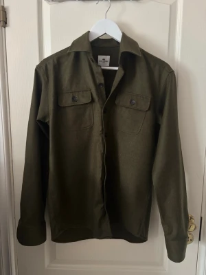 John Henric Overshirt  - Tjena! Säljer nu denna snygga och unika John Henric övershirt i färgen olive grön. Overshirten är iprincip aldrig använd och har inga defekter. Overshirten går knappt att få tag på längre och är perfekt nu till våren, lite tunnare overshirt med en skön passform, storlek S nypris: 1300kr, säljs för 650 kr