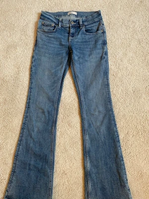 Blå bootcut jeans från Gina Tricot - Snygga blå jeans från Gina Tricot med coolt broderade fickor. Använda ett par gånger.💛