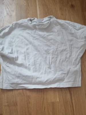 Vit croppad t-shirt från Zara - Enkel och stilren vit t-shirt från Zara i croppad modell. T-shirten har korta ärmar, rund halsringning med ribbad kant och är gjord i mjuk bomull.