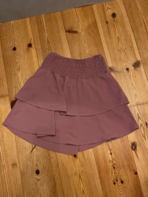 Ljuslila volangkjol med resårmidja - Supersöt ljuslila kortkjol med dubbla volanger och bred smockresår i midjan. Kjolen har en flowy känsla och passar perfekt till sneakers eller sandaler. Materialet känns lätt och luftigt, perfekt för varmare dagar.