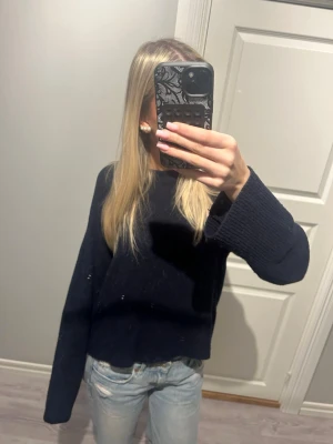 Mörkblå stickad tröja  - Mysig mörkblå stickad tröja med lite loose passform och vida, ribbade ärmslut. Perfekt att slänga på sig när det är kyligt ute. Enkel och stilren design som funkar till det mesta.