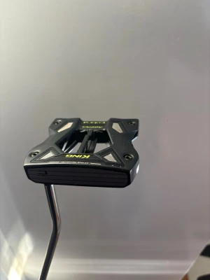 Cobra king supersport 120 putter  - Bilderna visar en golfklubba (putter) från Cobra, inte en väst. Klubban har svart och silver design med detaljer i gult och vitt samt ett grepp med mönster. Märket Cobra syns tydligt på greppet.