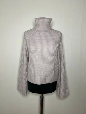 Ljuslila ribbad polotröja från H&M - Säljer en ljuslila ribbad polotröja från H&M i storlek S. Tröjan har hög polokrage, lång ärm och är stickad i ett mjukt material. Perfekt för kyliga dagar och enkel att styla med jeans eller kjol. Oanvänd