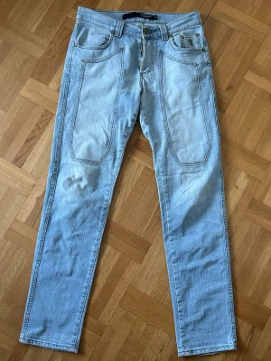 Ljusblå jeans från Jeckerson - Säljer ett par ljusblå jeans från Jeckerson med raka ben och unika stora fickor framtill åt min brorsa. Klassisk femficksmodell med bälteshällor och snygga kontrastsömmar. Jeansen är tillverkade i mjukt denimtyg och har en modern, avslappnad look. Skriv vid frågor! 