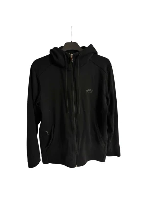 Snygg Hugo Boss hoodie i bra skick - Snygg svart Hugo Boss hoodie i storlek M, saknar 2 bokstäver på den lilla texten men ingenting som syns!