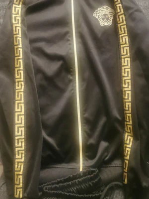 Träningsset  - Träningsset består av byxa och jackan. Tillverkades av polyester material, vilket ger den glänsande utseende. 