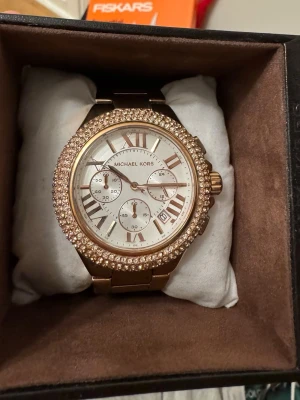 Michael kors klocka  - Klocka från Michael kors, knappt använd. Orginalförpackning, finns länkar att förlänga bandet med. Behöver ett nytt batteri annars toppenskick!