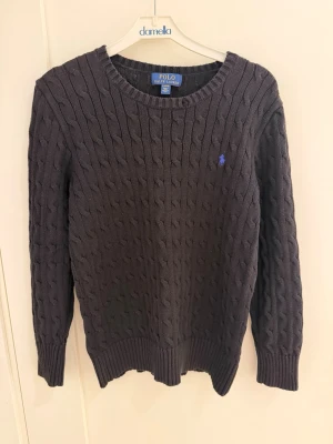 Mörkblå kabelstickad tröja Polo Ralph Lauren - Kabelstickad mörkblå tröja från Polo Ralph Lauren. Är i väldigt bra skick har inga skador eller fläckar. Pris kan diskuteras