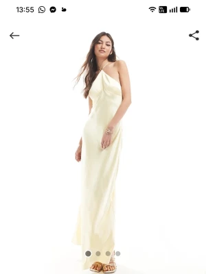 Ljus långklänning med halterneck - Supersnygg långklänning i ljus gul, Halterneck och slimmad passform. Klänningen har en elegant och enkel design som ger en lyxig känsla. Perfekt för sommarens alla tillfällen. Materialet Satin 