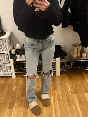 Ljusa  jeans från Zara - Säljer ett par ljusblå jeans från Zara med raka ben och hål vid knäna.  Med lågmidja. Pris går att diskutera. Liten defekt vid ena knät se sista bild.