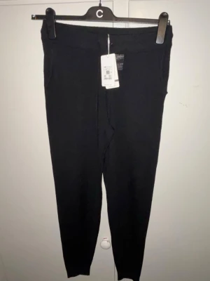 Svarta mjukisbyxor i merinoull - Svarta mjukisbyxor i extra fin merinoull med ribbade muddar vid benslut och midja. Byxorna har snörning i midjan och sidofickor. Perfekta för chill dagar och riktigt sköna mot huden.