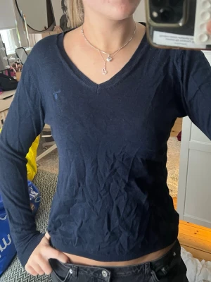 Mörkblå v-ringad tröja från Gant - Säljer en mörkblå långärmad tröja från Gant med v-ringning och diskret logga broderad på bröstet. Tröjan är tunn och mjuk, perfekt till både jeans och kjol. Klassisk och enkel modell som är lätt att matcha.