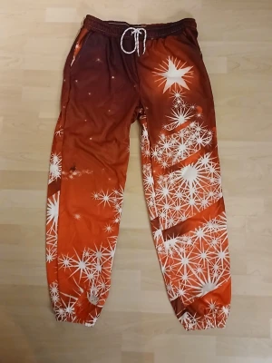 Orange röda mönstrade mjukisbyxor XL. Från Temu  - Säljer ett par mjukisbyxor i storlek XL med grymt coolt orange och rött mönster av vita stjärnor. Byxorna har snörning i midjan och resår vid bensluten. Tillverkade i 100% polyester, perfekta för chill dagar hemma. Från Temu!