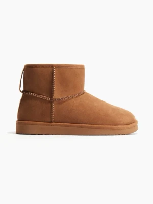 Bruna Uggs med rund tå - Mysiga boots i brun mocka med rund tå och platt sula. Skorna har synliga sömmar och en klassisk, enkel design som passar perfekt till kalla dagar. Insidan ser ut att vara fodrad för extra värme och komfort.