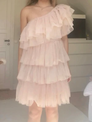 Volangklänning - Så himla snygg klänning i en typ peach färg. Perfekt som festklänning. Den är stretchig och passar flera olika storlekar xs-m. Fick den av min kusin som köpte den för några år sedan. Står inte märke eller storlek i