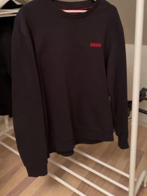 Svart sweatshirt/tröja från HUGO - Säljer en svart sweatshirt från HUGO med röd logga på bröstet. Tröjan har rund halsringning, långa ärmar och ribbade muddar. Perfekt för dig som gillar stilrena och klassiska plagg med en modern touch. Skick: Knappt använd, max 1-3 gånger 😁storlek: XL, sitter lite stort på mig som har L. Priset går att diskuteras👍                             📦Skickas snabbt!