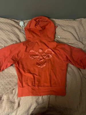 Kortärmad tjocktröja  - Kortärmad tjocktröja från hummel. Köpt från Sellpy. Den är lite mera rosa än orange men den ser orange ut på bilden. Priset kan sänkas
