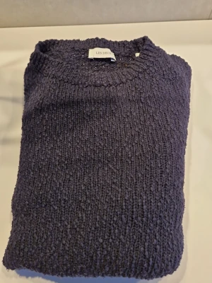 Mörkblå stickad tröja Les Deux st 146/152 - Säljer en mörkblå stickad tröja från Les Deux med grov struktur och broderad logga i vitt vid nederkanten. Tröjan har rund hals och långa ärmar, perfekt för kyliga dagar. Passformen är normal och materialet känns mjukt och värmande. Köpte denna i Frankrike för 1200 kr och har använts ett par gånger. Har du frågor är det bara att skriva. 