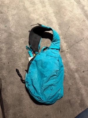 Turkos ryggsäck från Craghoppers - Säljer en turkos ryggsäck från Craghoppers med justerbara remmar och flera fack med dragkedja. Väskan har en sportig design och mesh-detaljer på baksidan för extra komfort. Perfekt för dig som vill ha en smidig och lätt väska till vardagen.