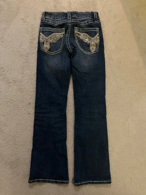 Mörkblå jeans med broderade fickor - Säljer ett par justerbara blåa jeans med bootcut passform ifrån Gina tricot young i storlek 146❤️ fickor med vingar på, du får betala frakten! nypris: 359kr 