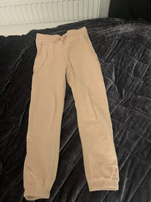 Beige/rosa mjukisbyxor med snörning - Beige/rosa mjukisbyxor från 157 med elastisk midja och snörning i storlek 150. Byxorna har ribbade muddar i midjan och är riktigt sköna.  Funderingar? Skriv till mig💕